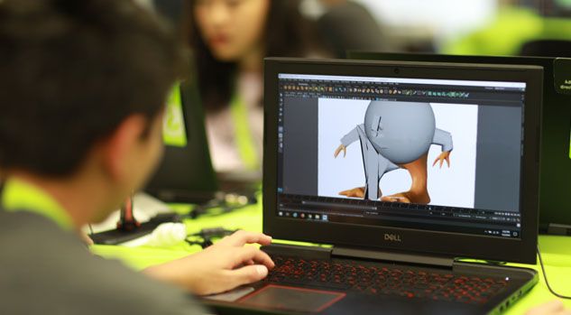 over shoulder of boy working on character model on laptop