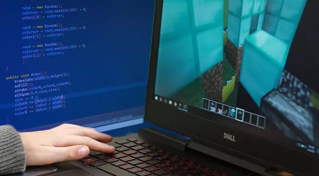hand on laptop keys with minecraft on screen