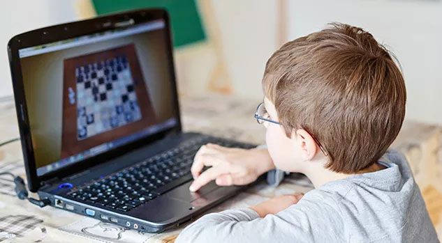 boy at laptop playing chess